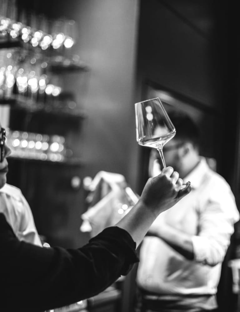 A sommelier examining a glass of wine against the light at Frasca Food and Wine