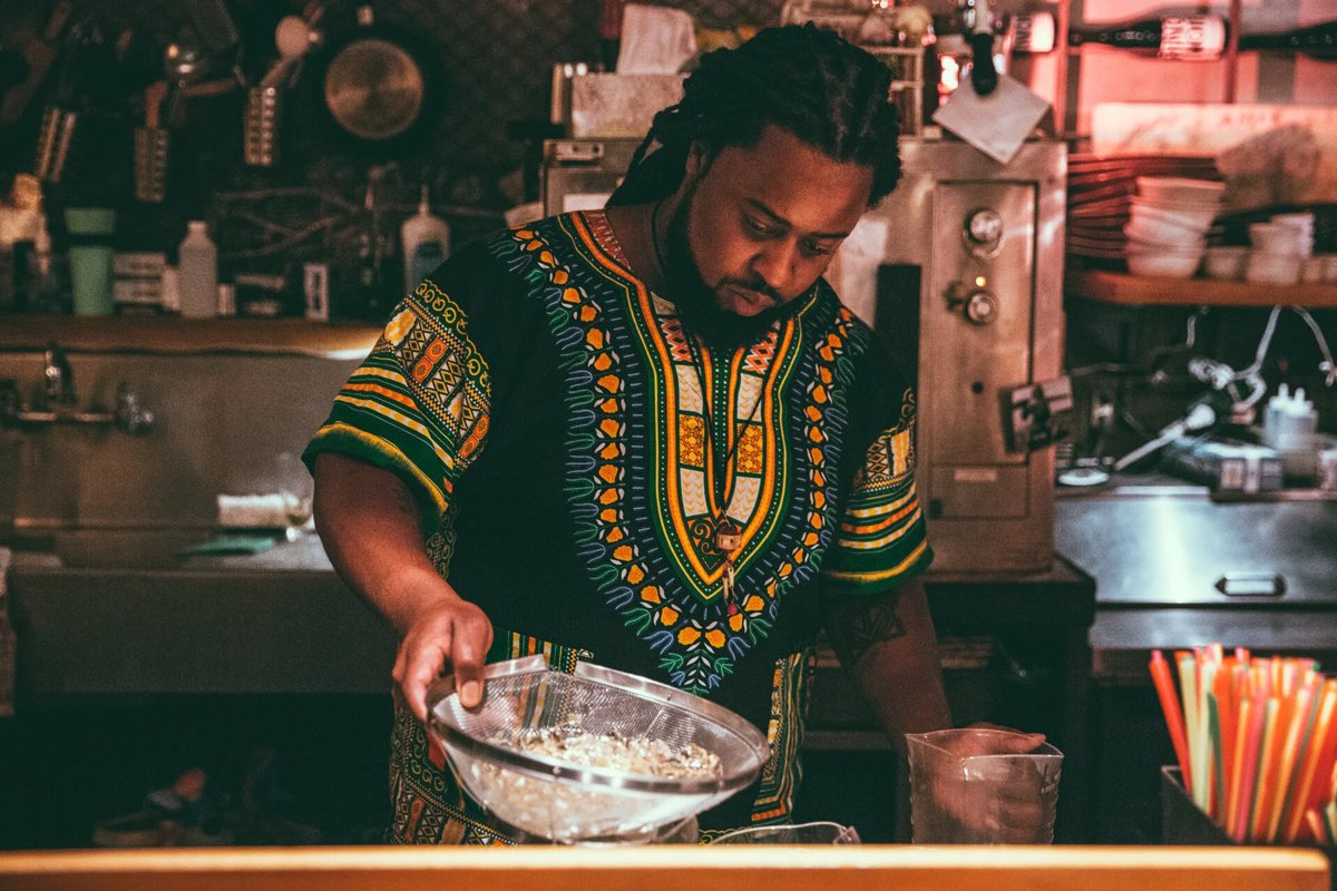 Damon Bomar, co-owner and general manager of Communion, straining a cocktail behind the bar