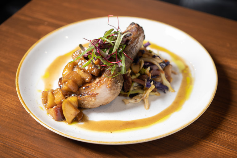 A plated Communion dish: grilled pork chop with stewed apples and braised cabbage