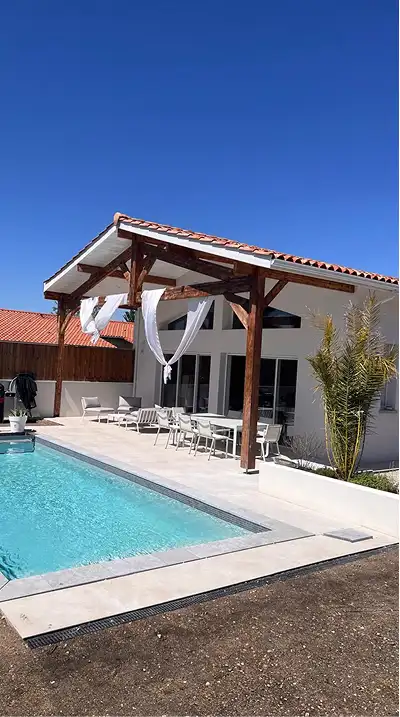 alt="maison rénovée avec terrasse couverte en charpente bois et piscine à Bassens près de Bordeaux"
