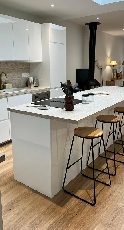 alt="cuisine rénovée avec îlot central et plaque de cuisson intégrée dans une cuisine blanche sur mesure à Bordeaux"