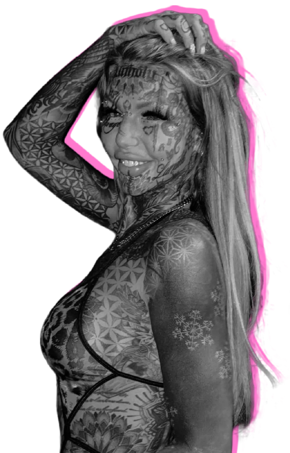 Woman with extensively tattooed face, arms, and torso, smiling with one hand in her long hair.