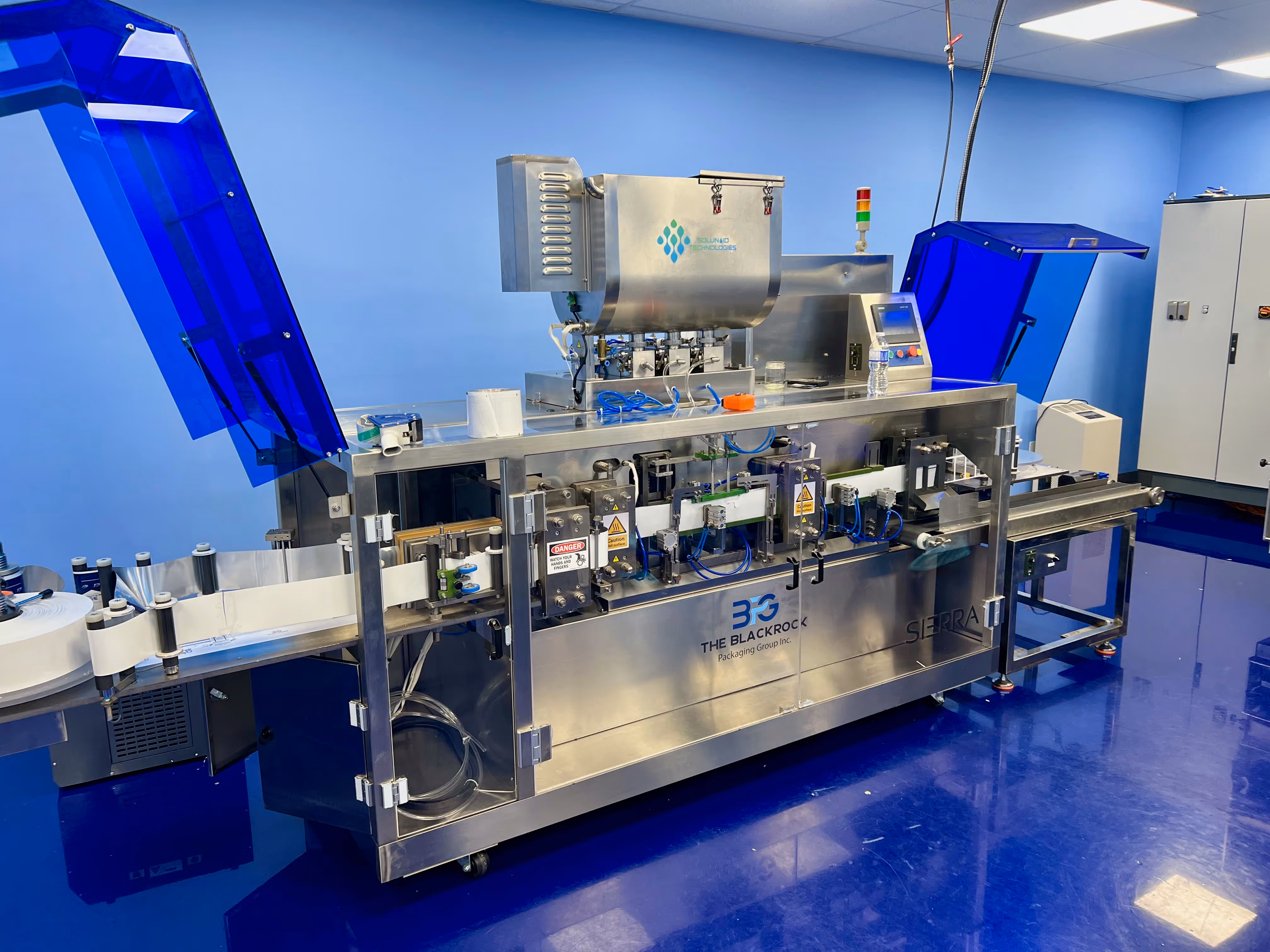 Stainless steel industrial packaging machine with conveyor belts in a blue-walled room.