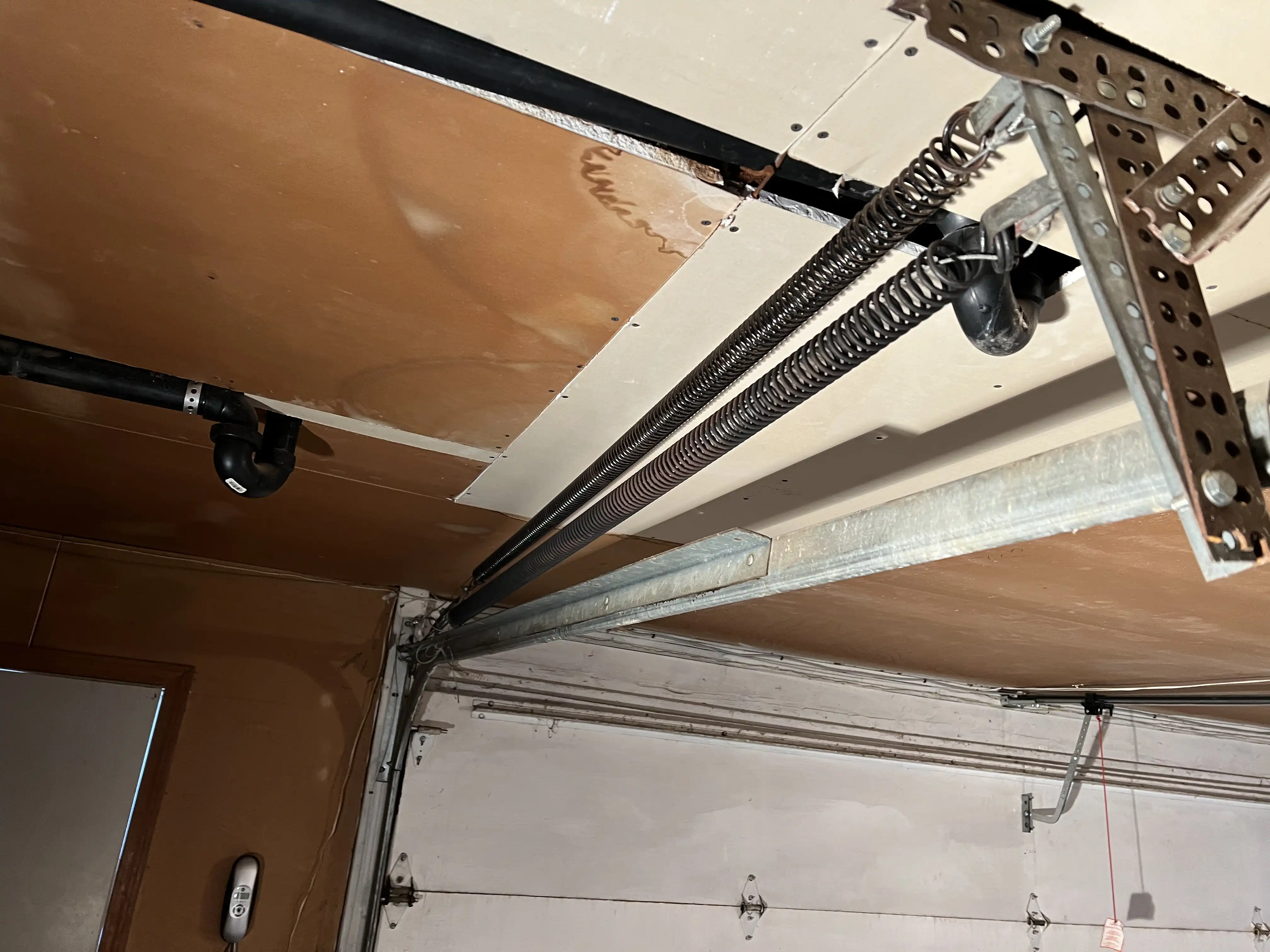 Older garage door with extension springs in Paola, KS before torsion conversion