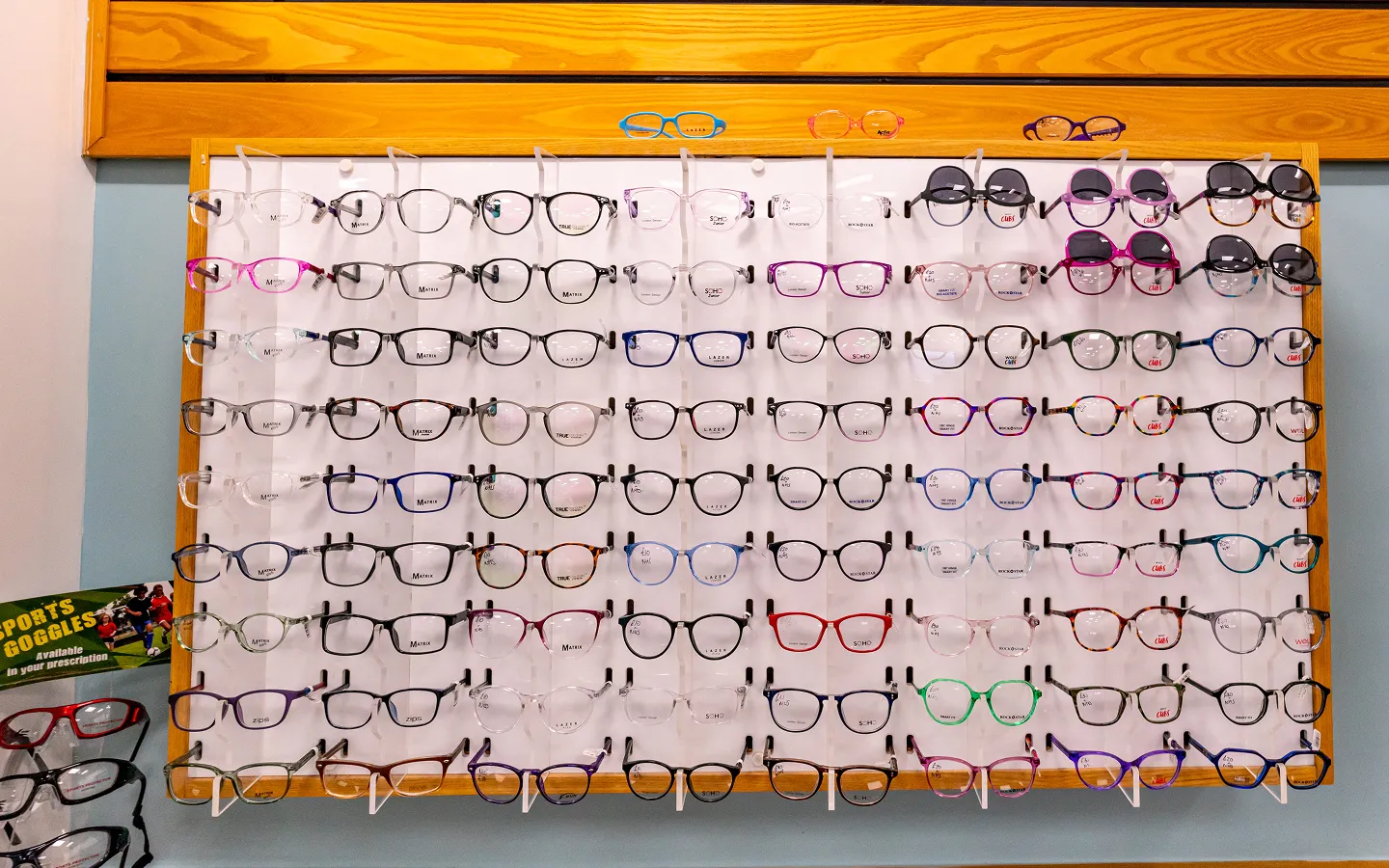 Display board with multiple rows of assorted eyeglasses and sunglasses in various colors and styles.