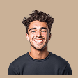 Smiling young man with curly dark hair wearing a black shirt against a beige background.