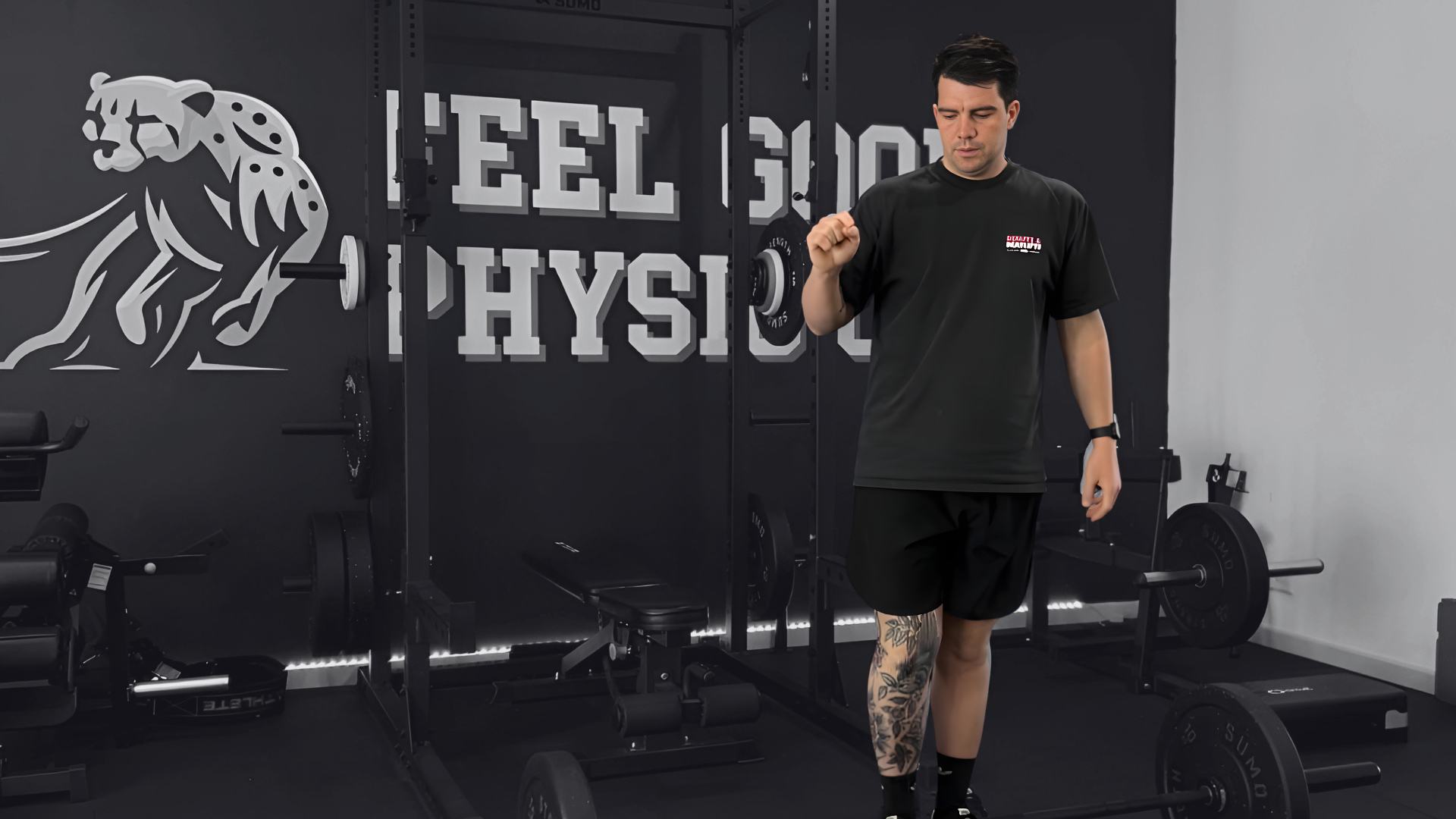 Man in black shirt demonstrating weighhtlifting stance in professional gym facility