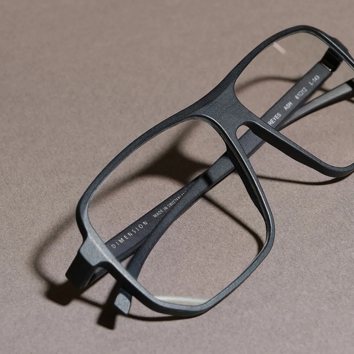 Black rectangular eyeglasses with the text 'DIMENSION' and 'Made in Switzerland' on the temple.