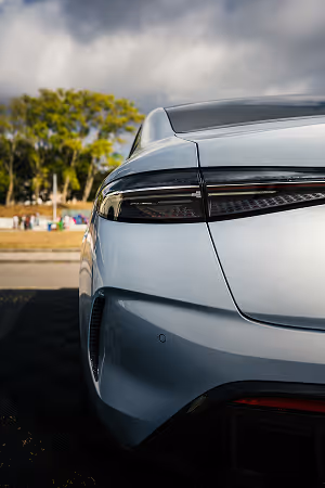 Close-up of the rear left side of a sleek silver electric car with modern tail light design, parked outdoors.