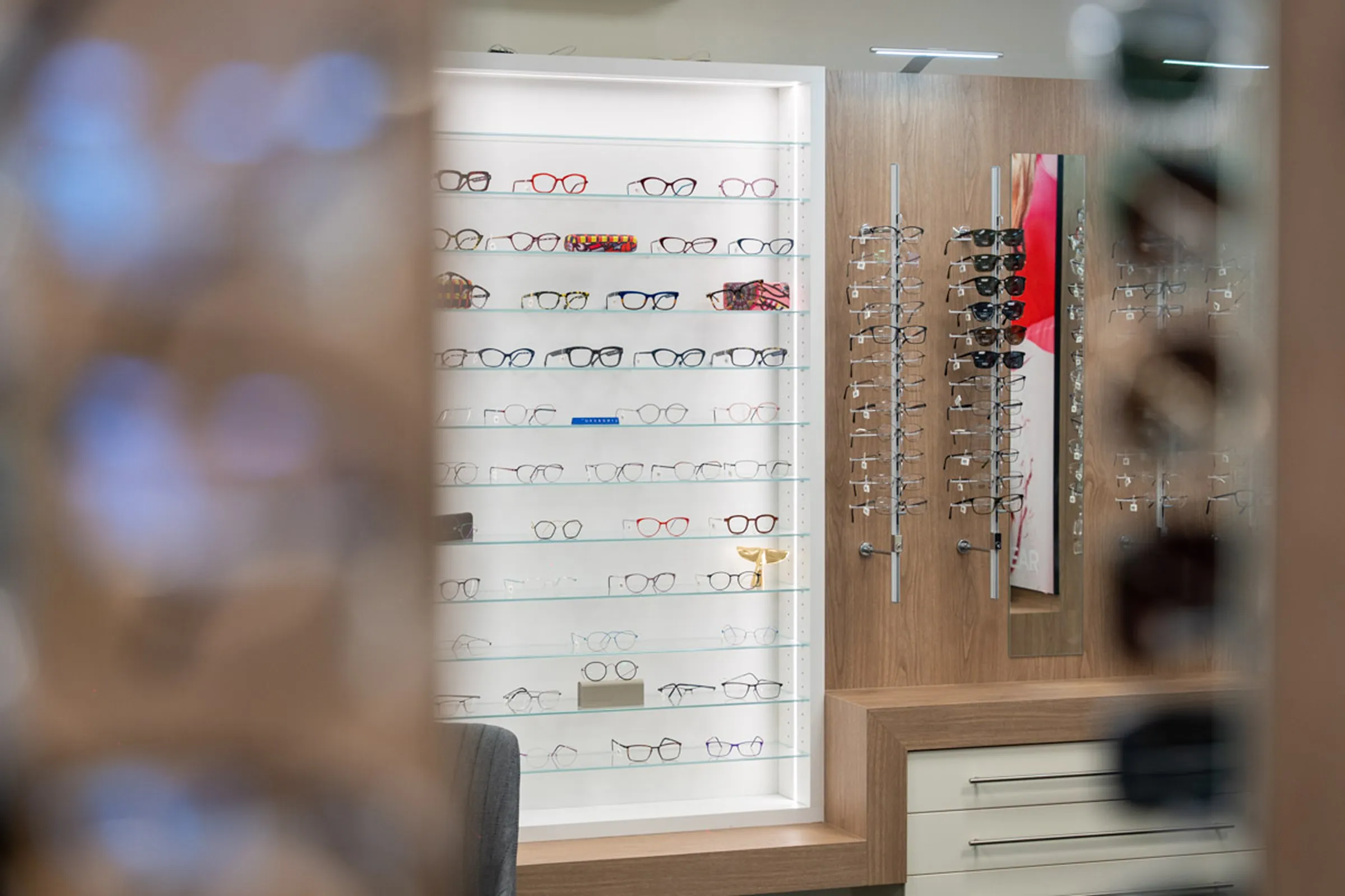Display shelves and racks showcasing various eyeglass frames in an optical store.