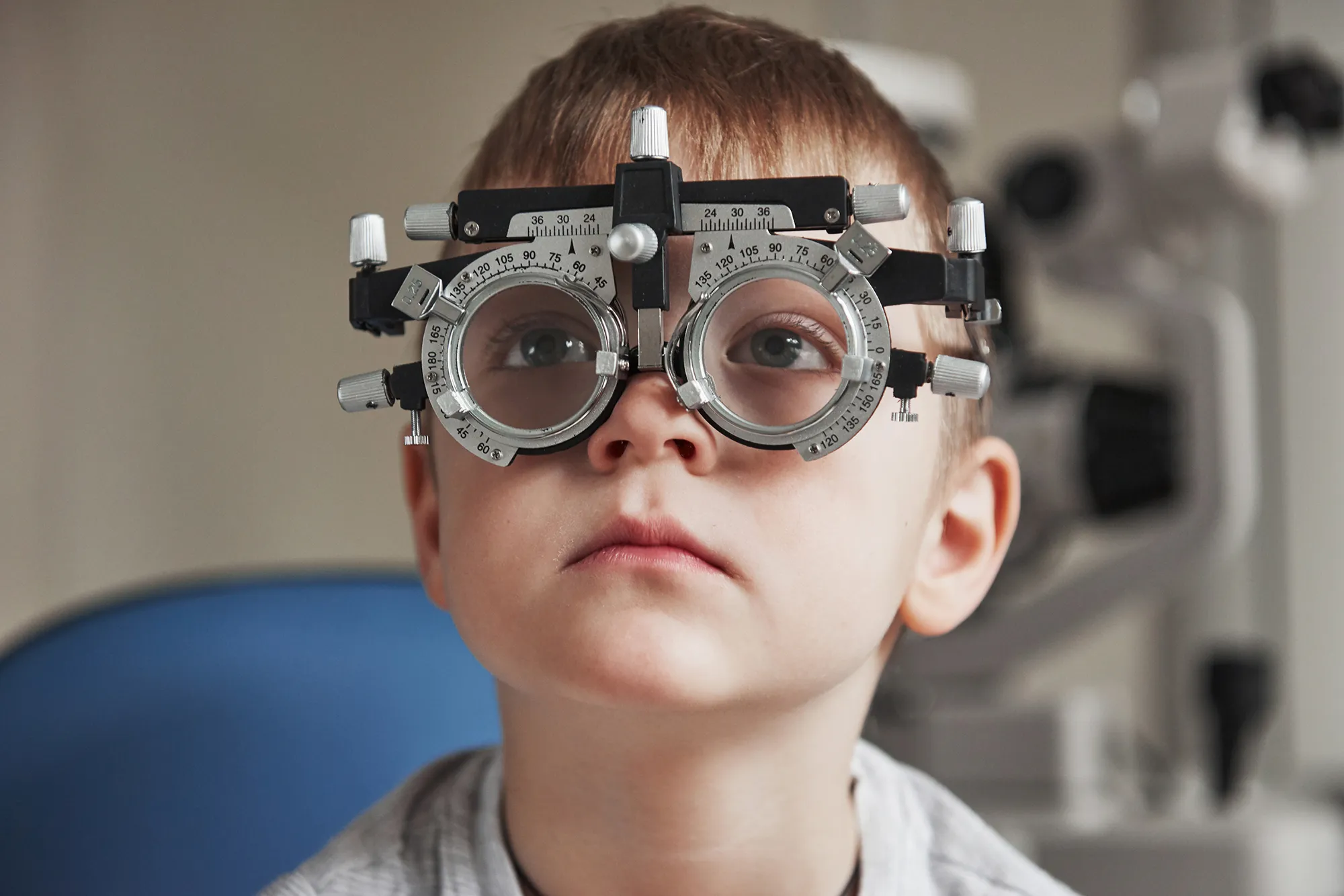 Child wearing a trial frame during an eye examination in an optometry clinic.