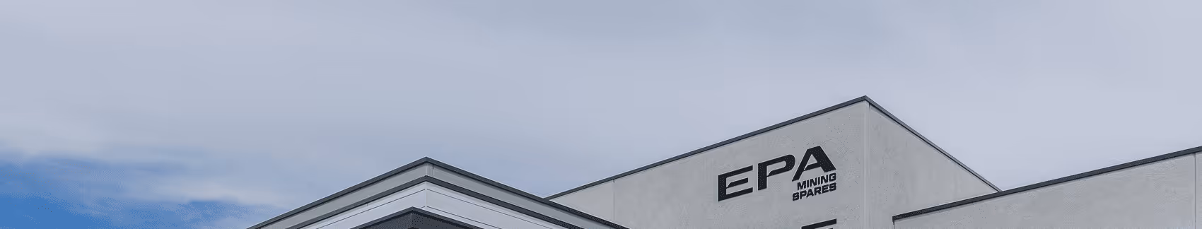 Modern building corner with 'EPA Mining Spares' logo on the exterior wall under a cloudy sky.