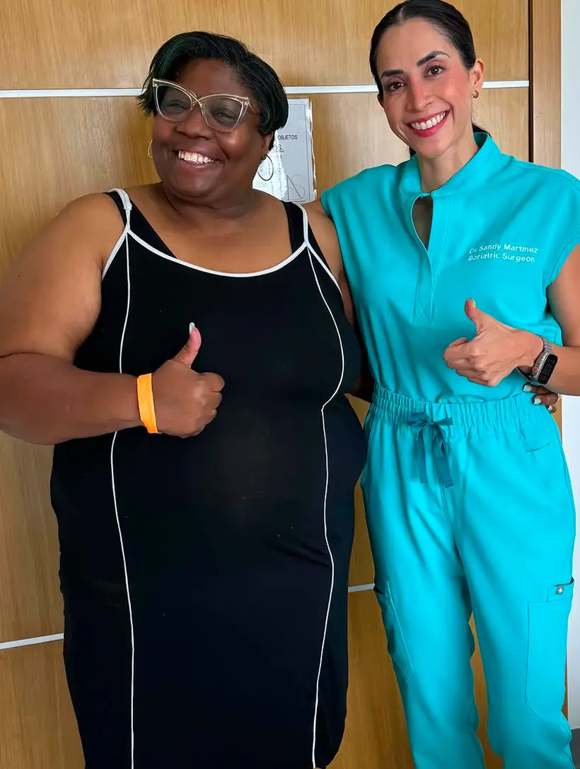 Dr. Sandy Martinez, bariatric surgeon, giving a thumbs up with a happy patient in a black dress, celebrating a life-changing weight loss transformation in Tijuana.