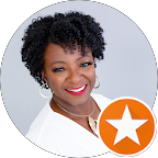 Portrait of a smiling woman with curly black hair wearing hoop earrings and a white top against a light background.