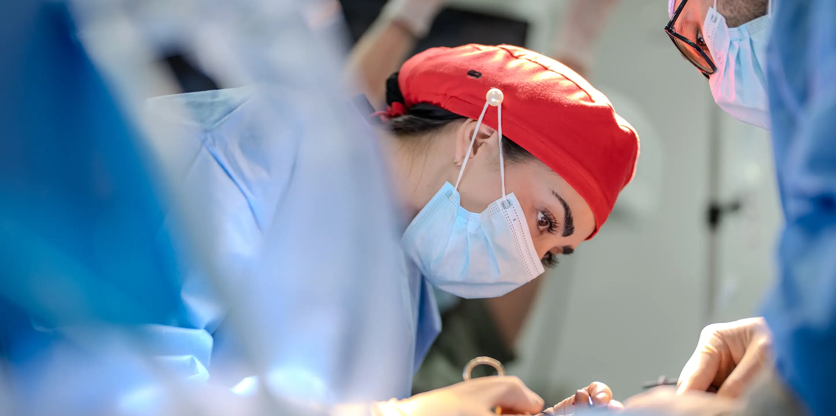 "Dr. Sandy Martinez and her expert bariatric team, wearing masks and red surgical caps, performing a safe weight loss surgery in a state-of-the-art operating room.