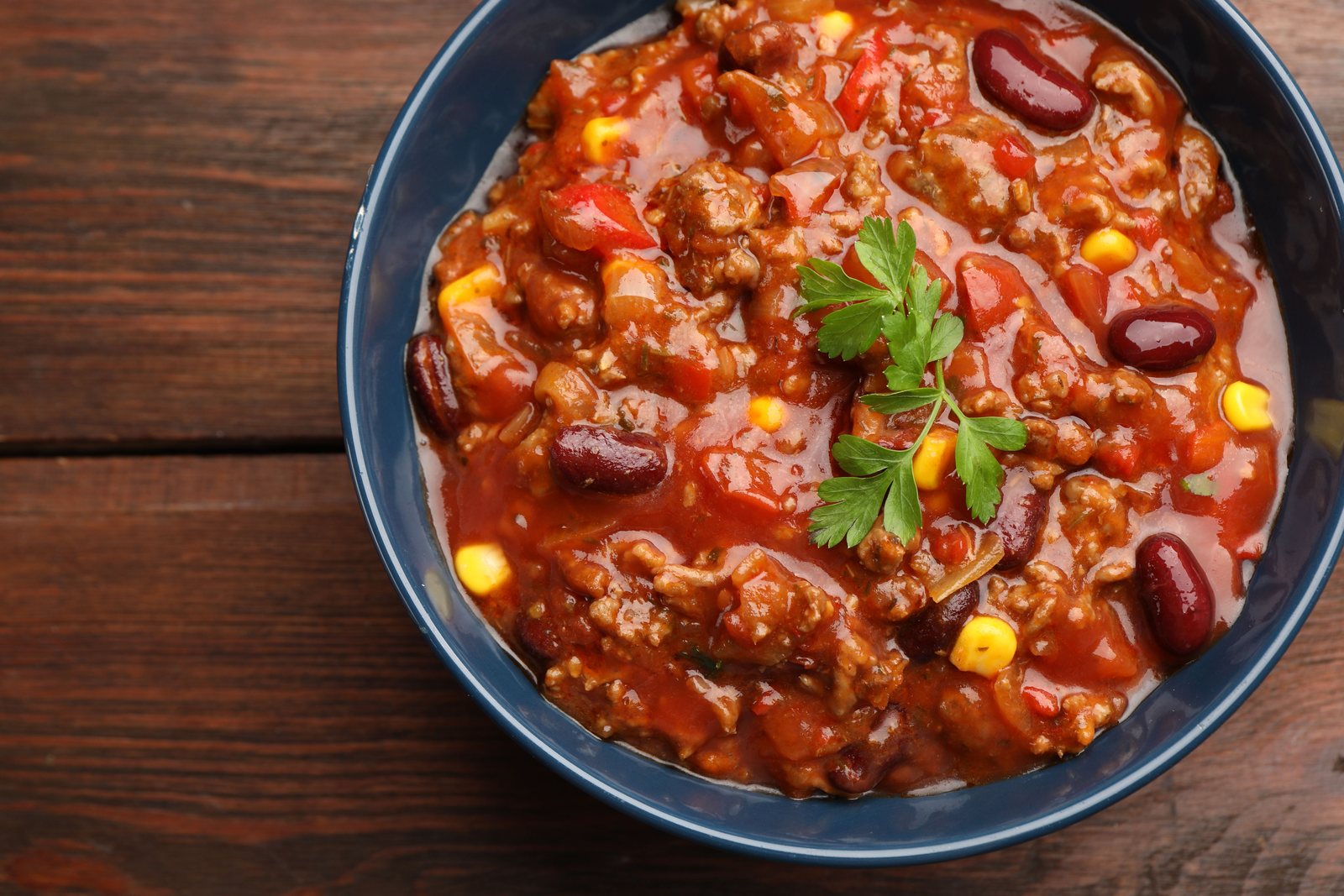 A bowl of chili with beans and corn in a navy bowl