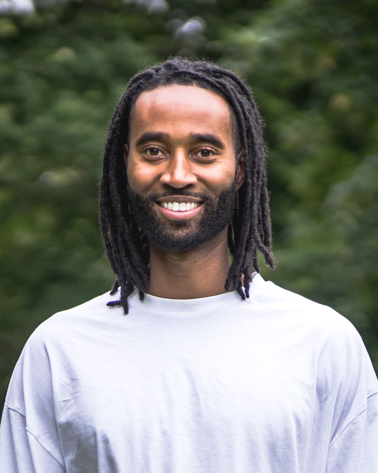 Dr Lewis Thomas smiling outdoors, founder of Sickleverse and sickle cell educator