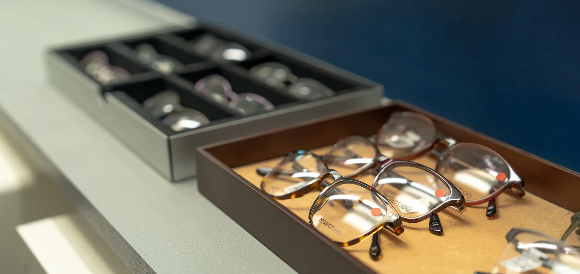 Tray of prescription eyeglasses with clear lenses and brown frames on a display table.