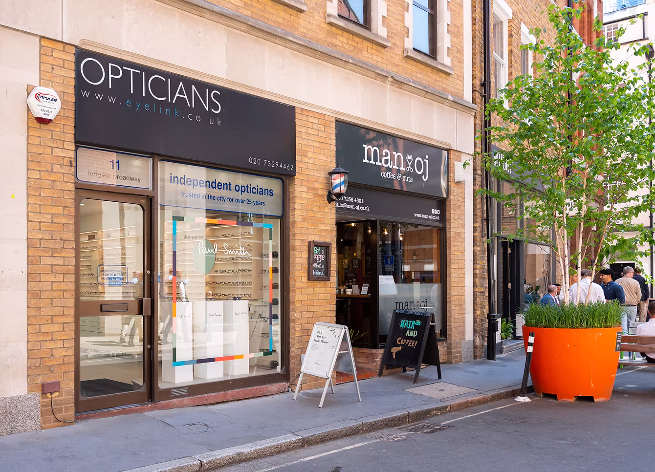 Street view of an optician store next to a coffee and haircut shop called manoj.