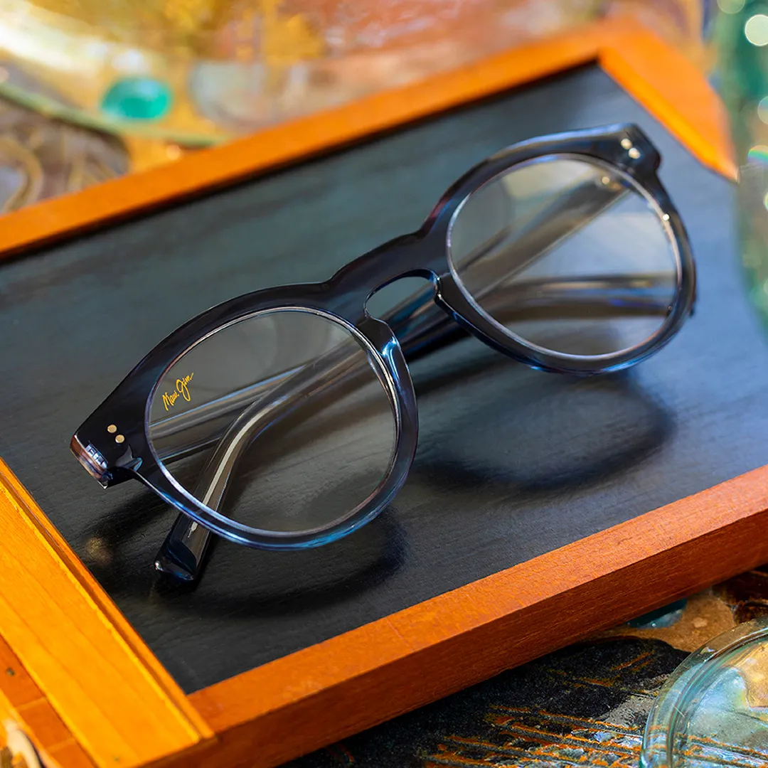 Black-framed round eyeglasses with Marl Jim logo, placed on a black tray with a wooden border.