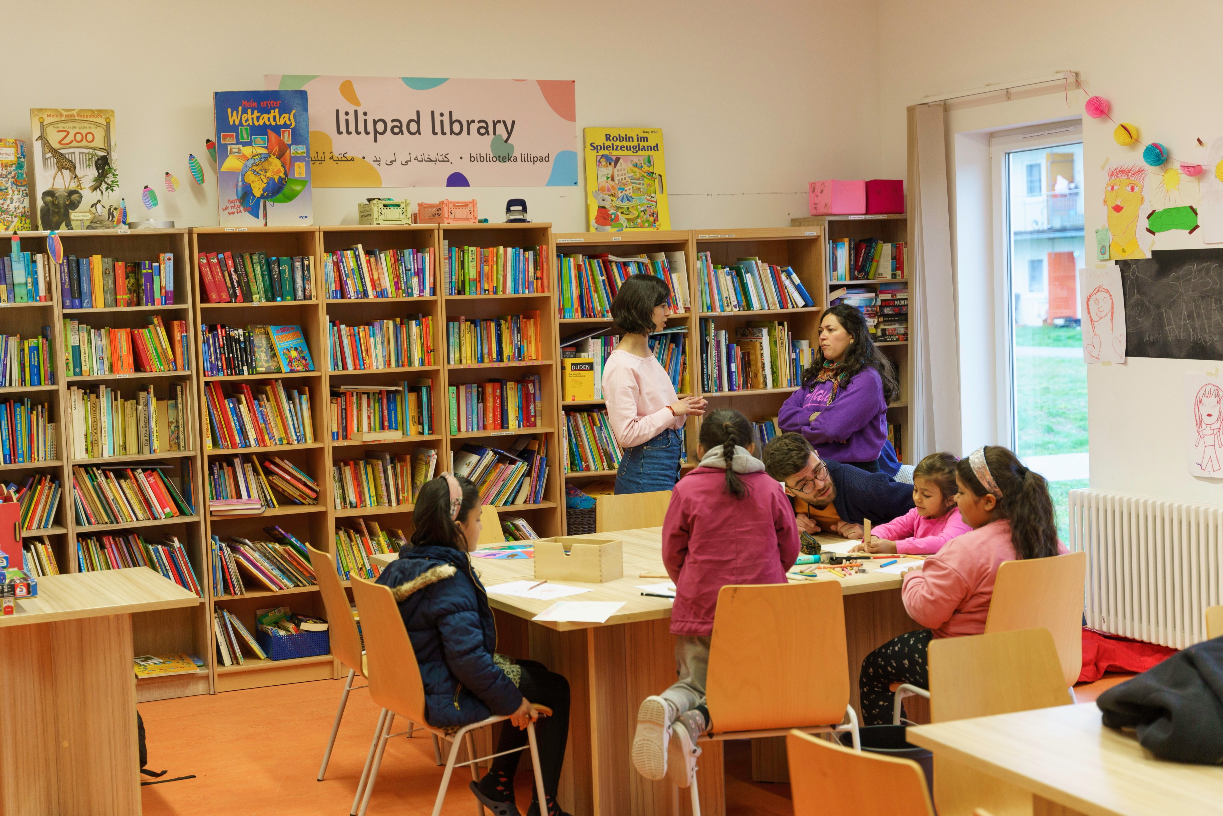 Eine Gruppe lächelnder Kinder im Freien, die Friedenszeichen machen und den Daumen hochhalten.