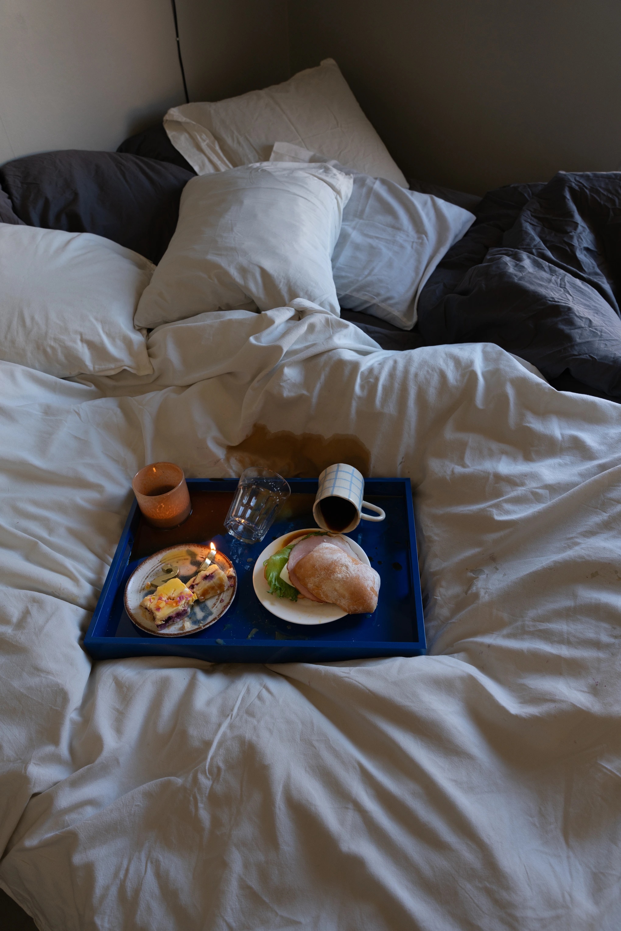Frukostbricka i en säng med spilld dryck och omkullvält kopp.