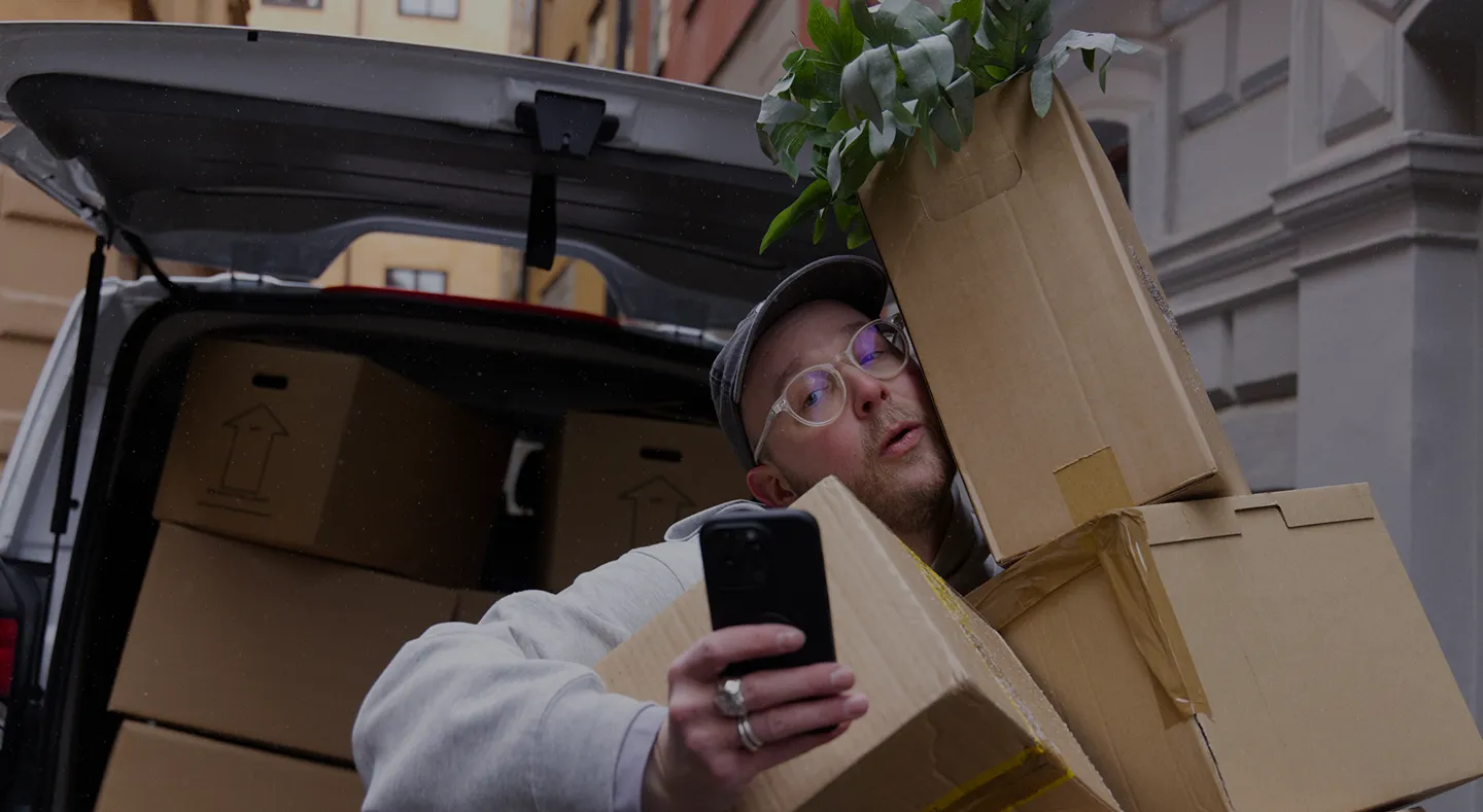 Kvinna med lockigt blont hår i grå tröja och blå byxor sitter i soffa med leopardmönstrad filt och gitarr bredvid.