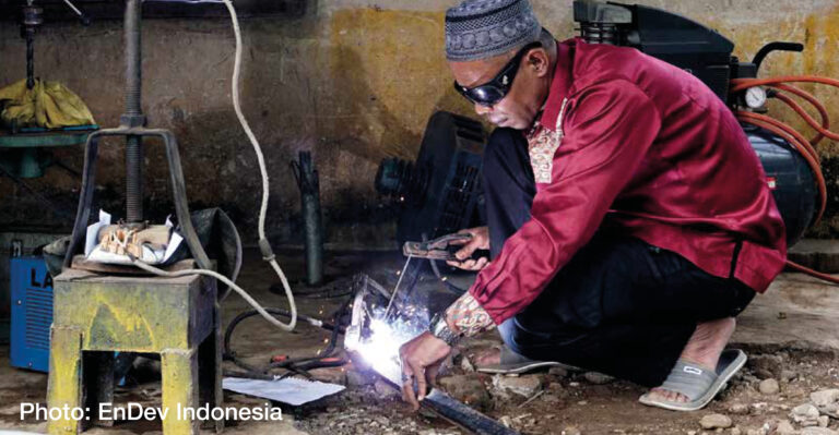 Indonesian man working on electrics in the surroundings of a rural house