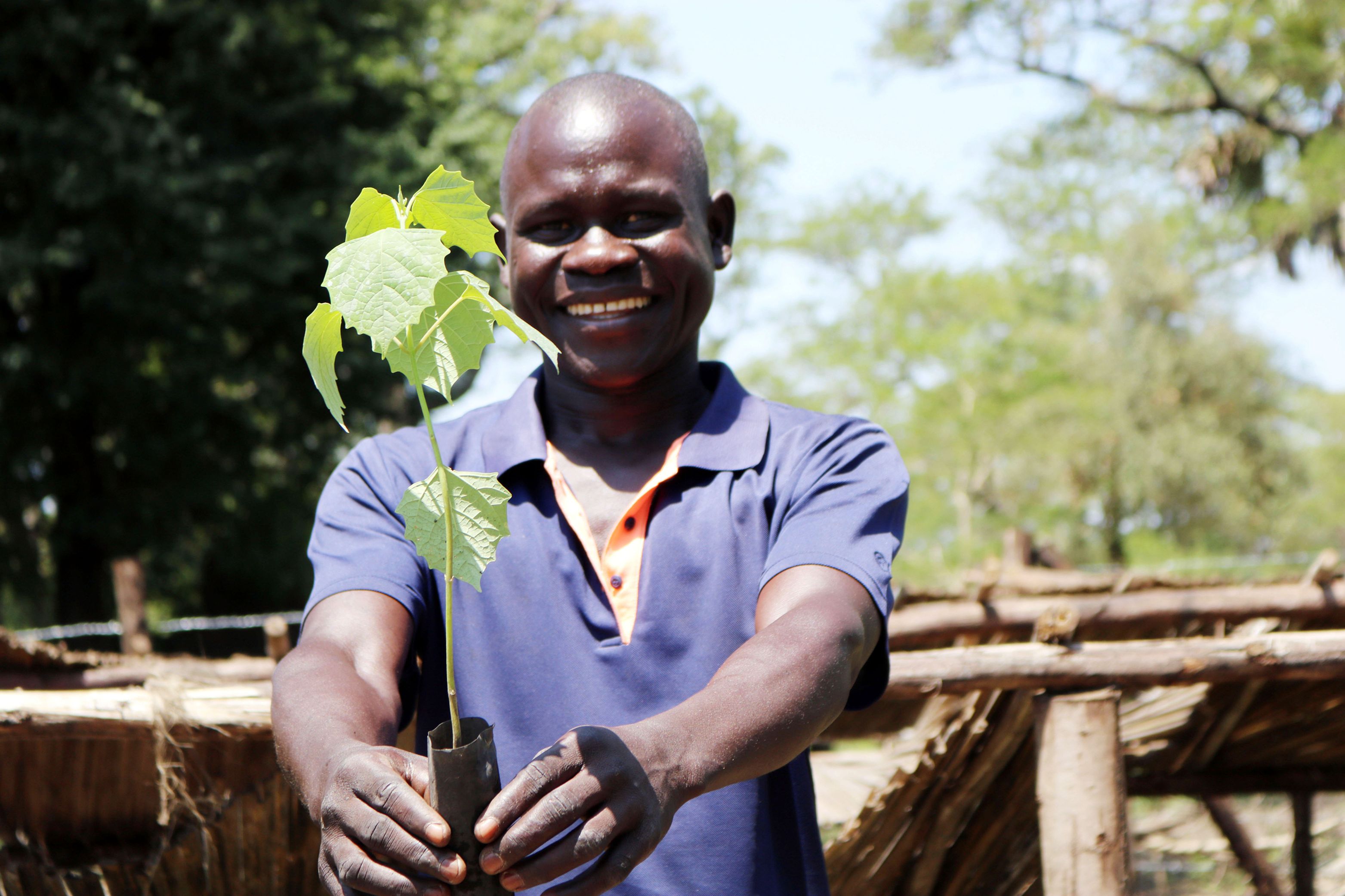 A smiling man with a green plant in his hands