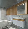 bathroom remodel with wooden accents, featuring a large mirror, white vanity with wooden drawer, and a bathtub with a showerhead.