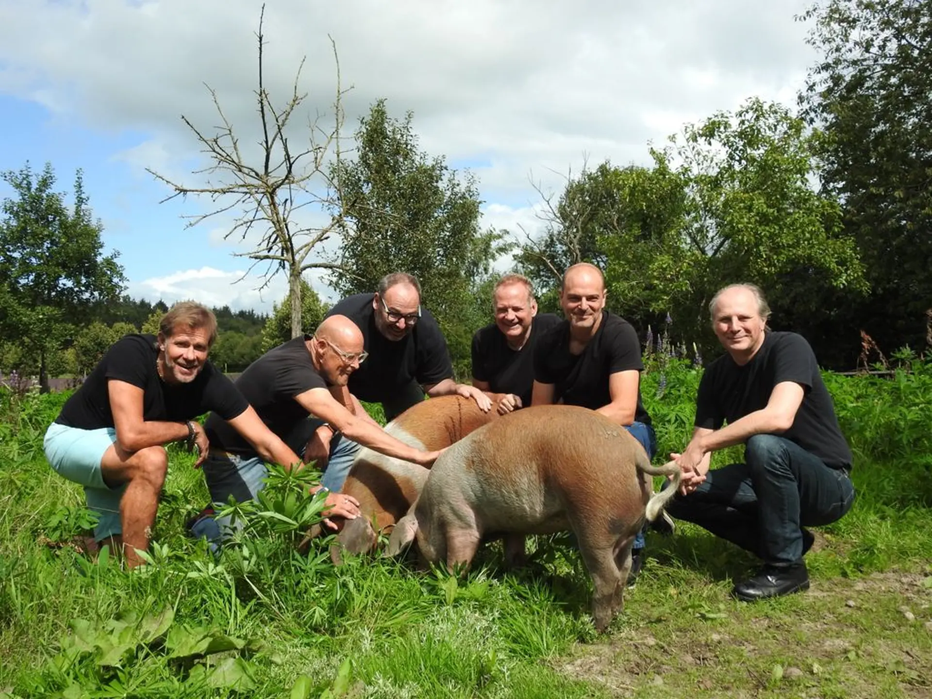 a group of men kneeling down next to a pig