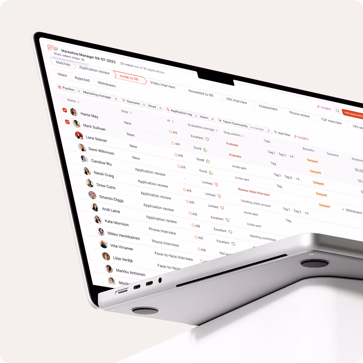 Laptop displaying a recruitment management interface with candidate names, statuses, evaluation scores, and interview steps for a Marketing Manager position.