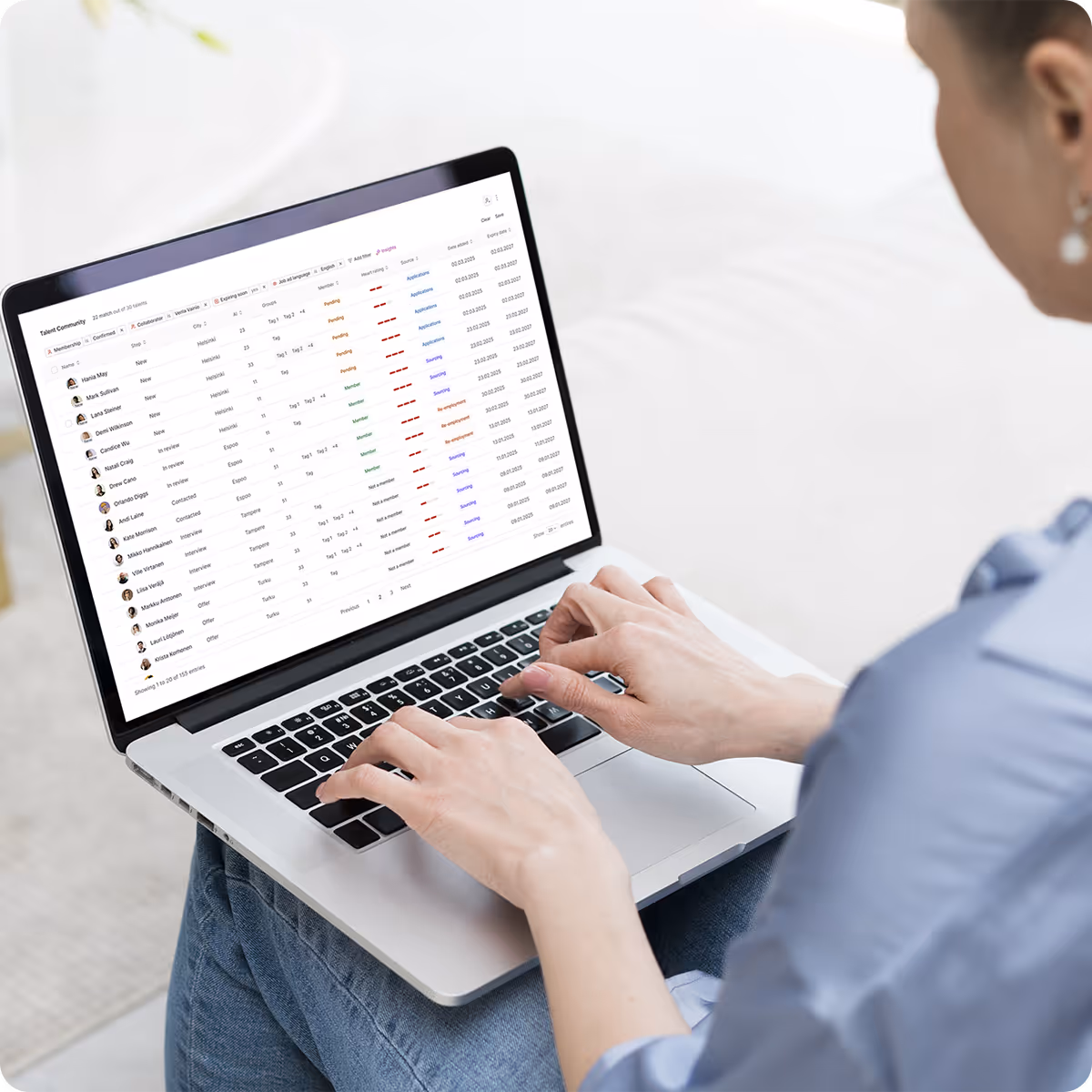 Person typing on a laptop displaying a talent community management dashboard with names and statuses.
