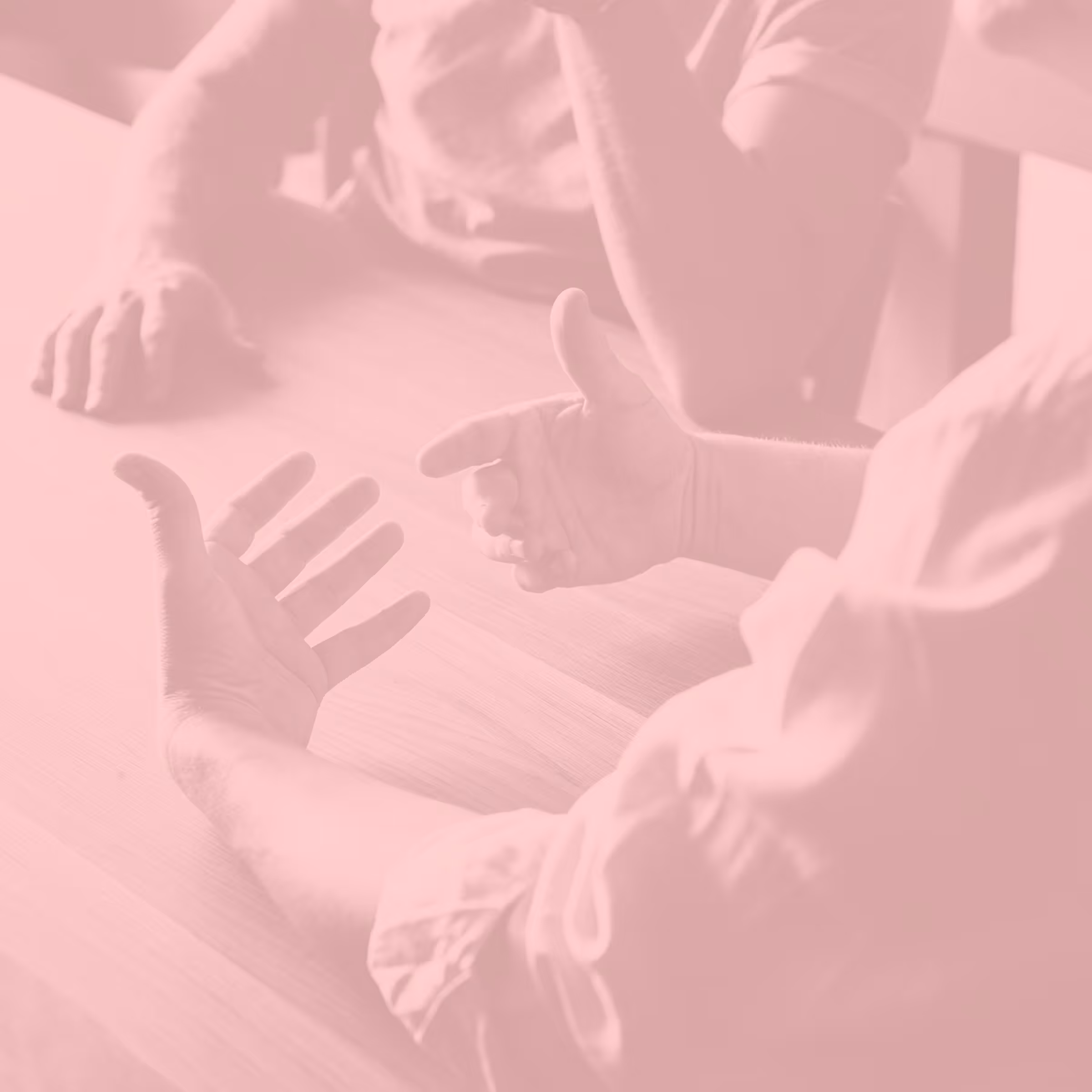 Two people seated at a table engaged in a discussion using expressive hand gestures.