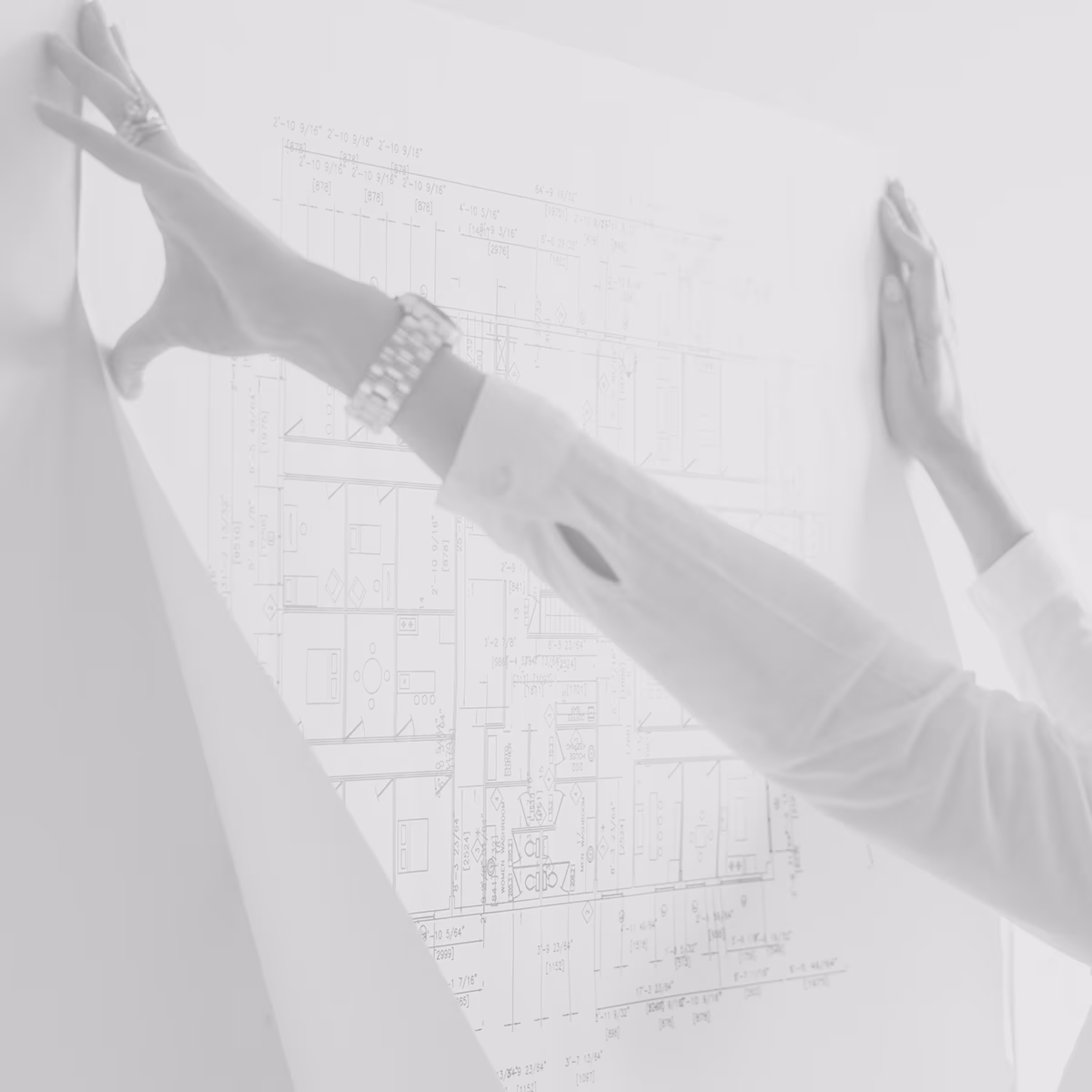 Person holding and examining a blueprint or architectural plan on a wall.