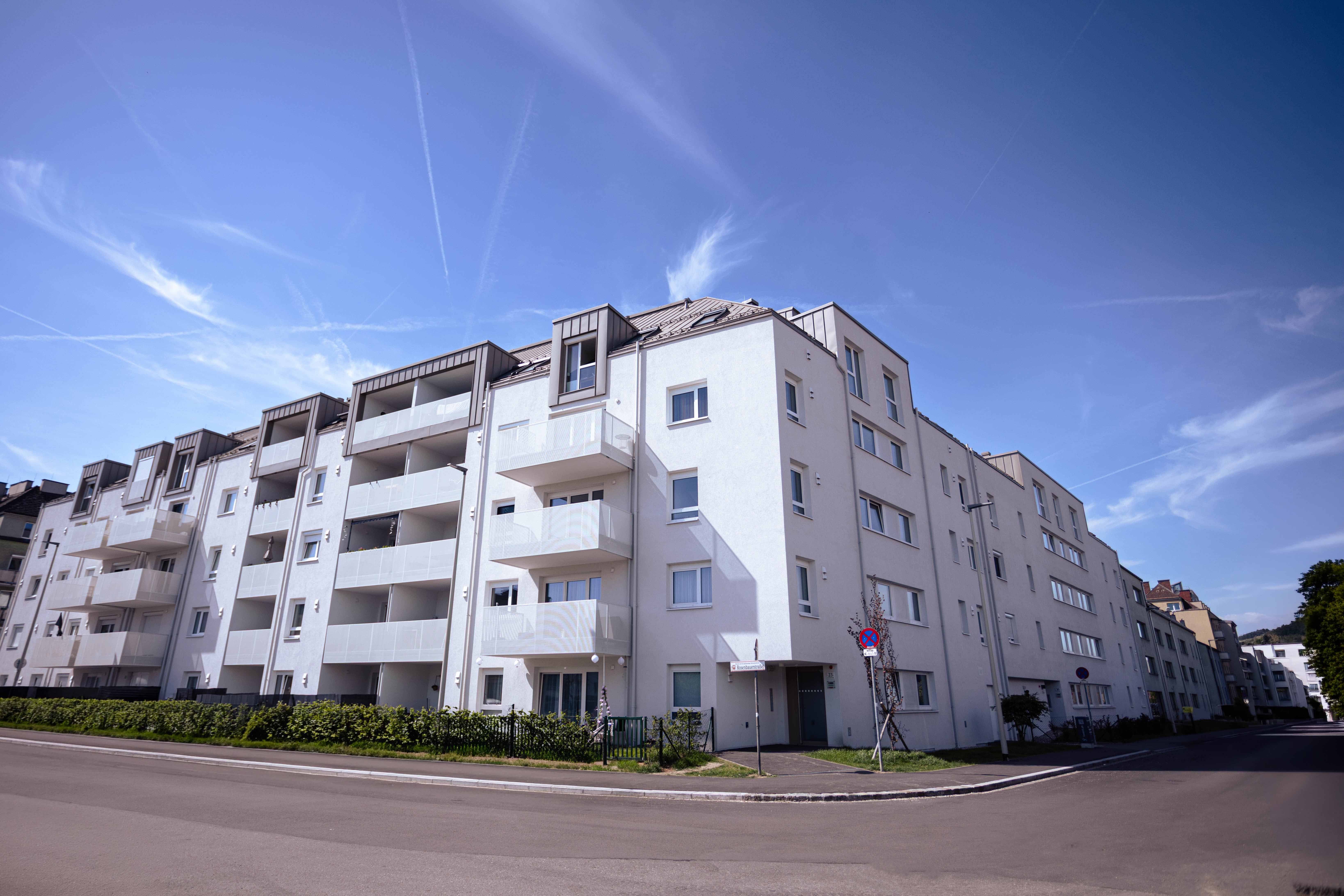 Mehrstöckiges modernes Wohngebäude mit hellen Fassaden und Balkonen bei klarem Himmel.