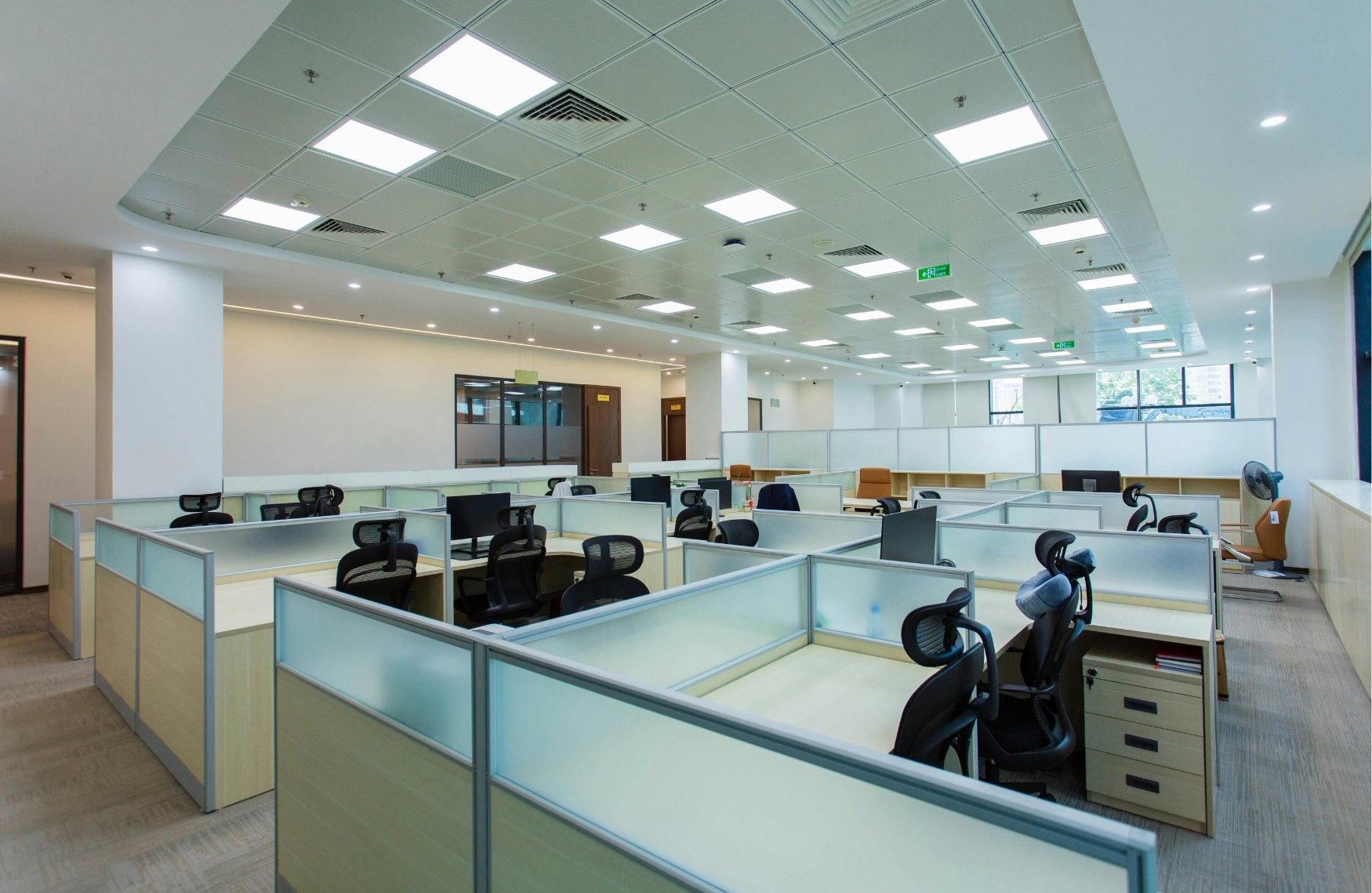 Open-space de bureaux à Genève, rangé et lumineux, postes de travail propres, grande baie vitrée donnant sur la rade, ambiance professionnelle sobre et moderne