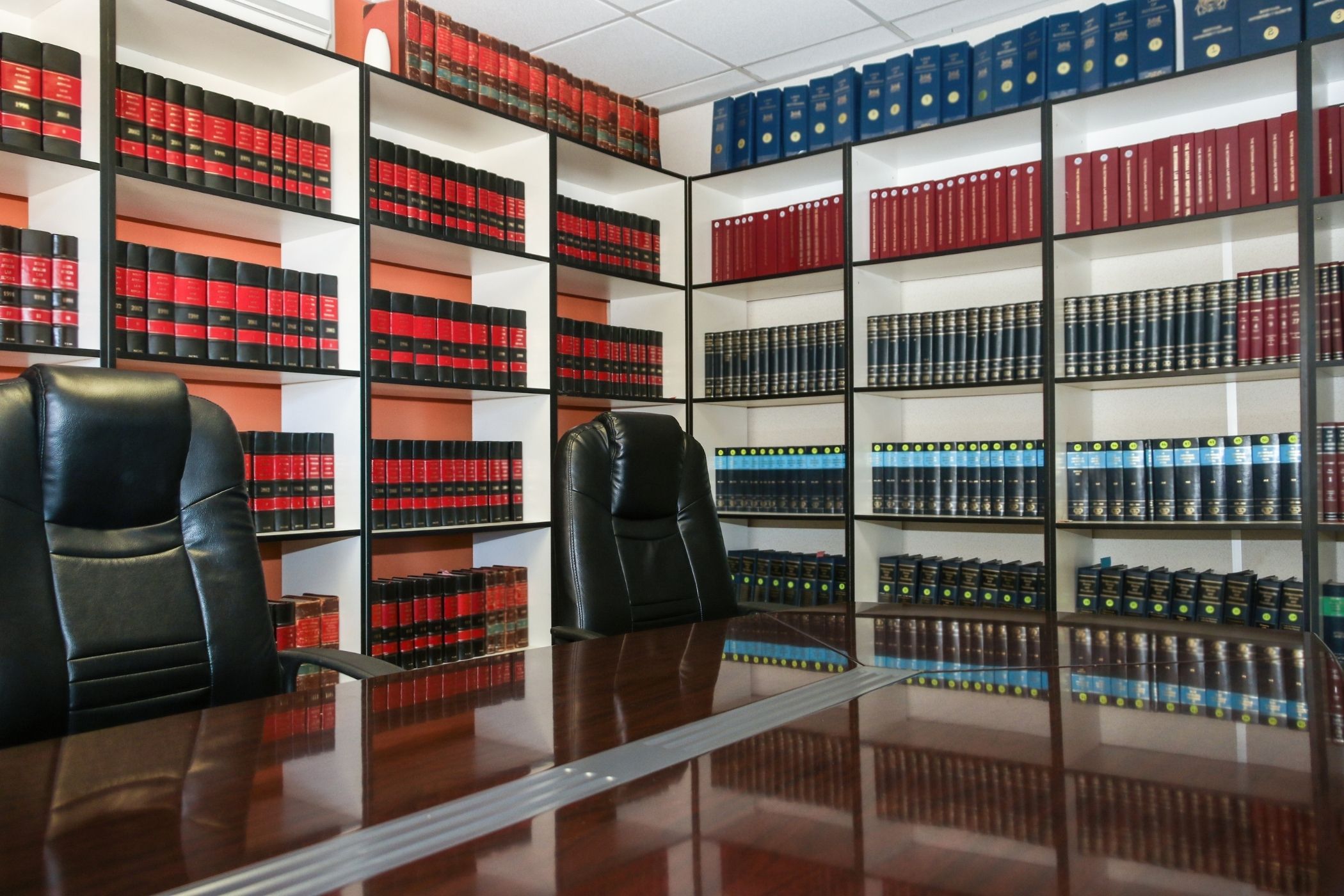 Vue d'une salle de réunion de cabinet d'avocats haut de gamme à Genève : table en bois foncé impeccable, chaises en cuir, vitres sans traces, lumière tamisée, ambiance professionnelle et discrète.