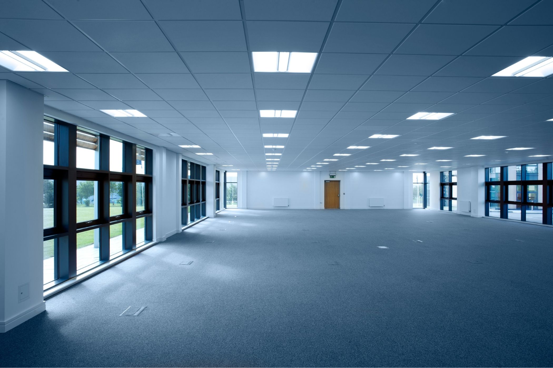 Vue d'un bureau vide après débarras complet à Nyon : sol propre, murs blancs impeccables, fenêtres ouvertes, lumière naturelle, espace libéré prêt pour l'état des lieux, ambiance restitution réussie.