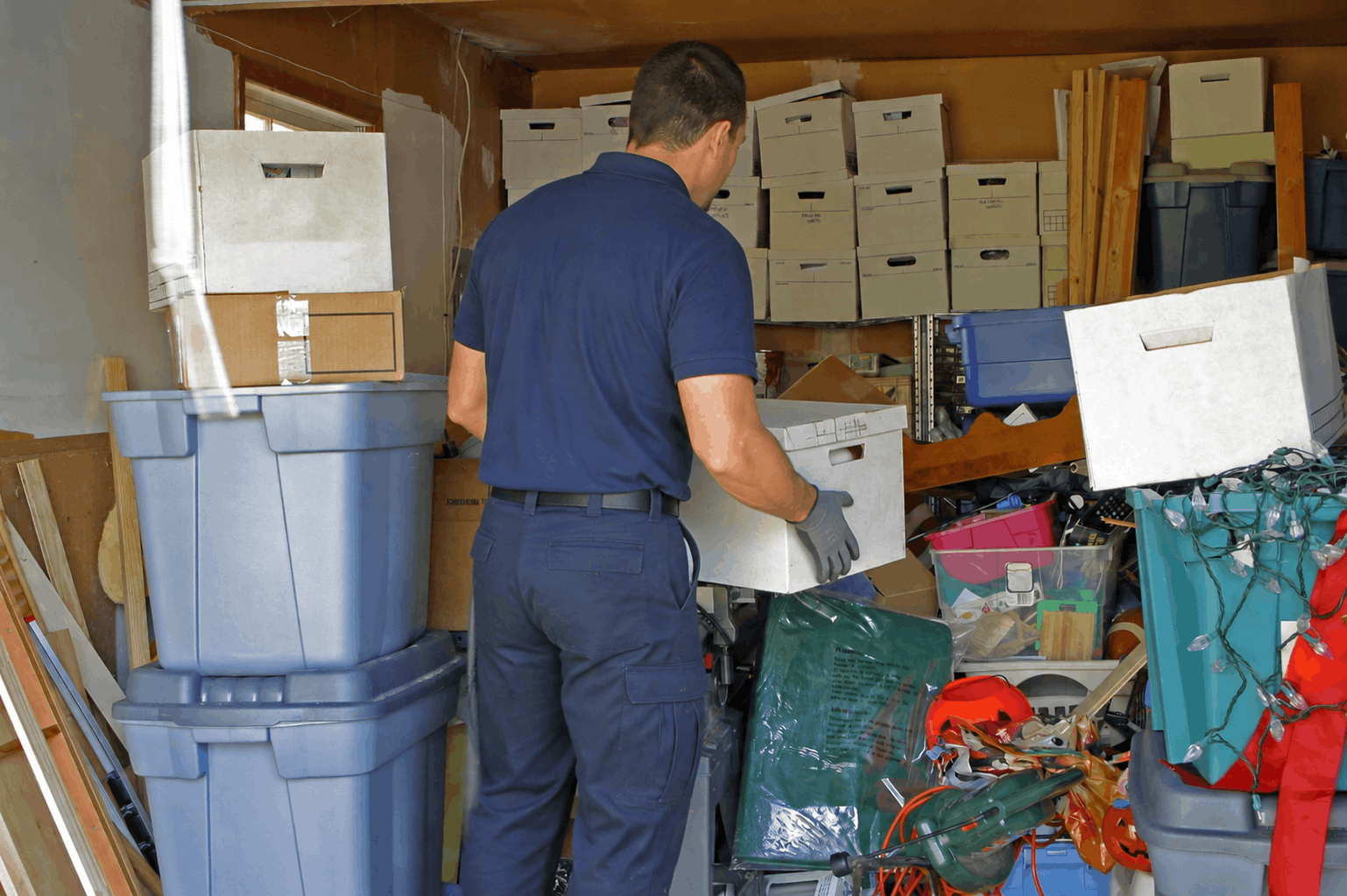 Équipe de débarras professionnelle évacuant des cartons et du mobilier d'une cave de copropriété, ambiance organisée et efficace, journée claire.