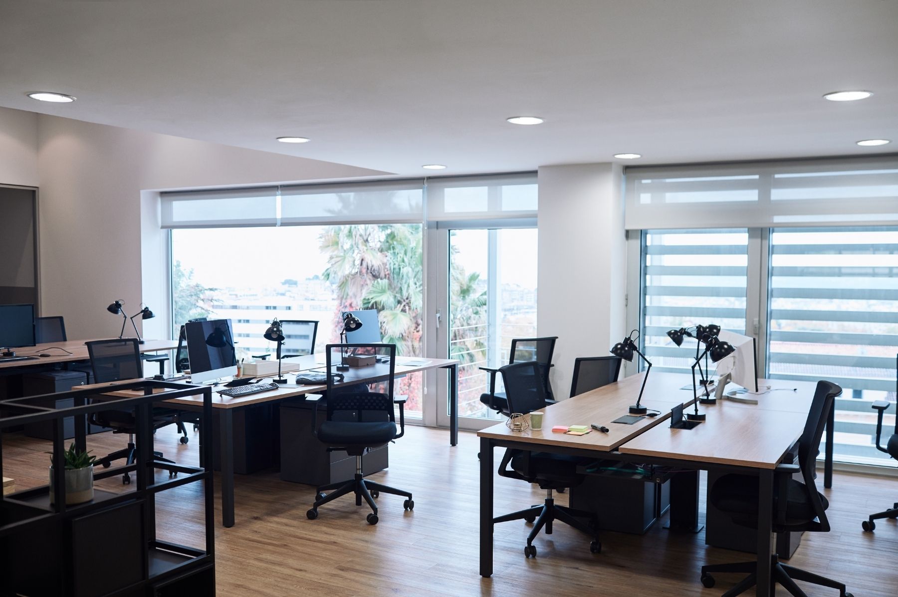 Vue d'un open-space lumineux et impeccable à Lausanne, bureaux vides prêts pour la rentrée, sol brillant, plantes vertes, lumière naturelle, ambiance professionnelle et accueillante.