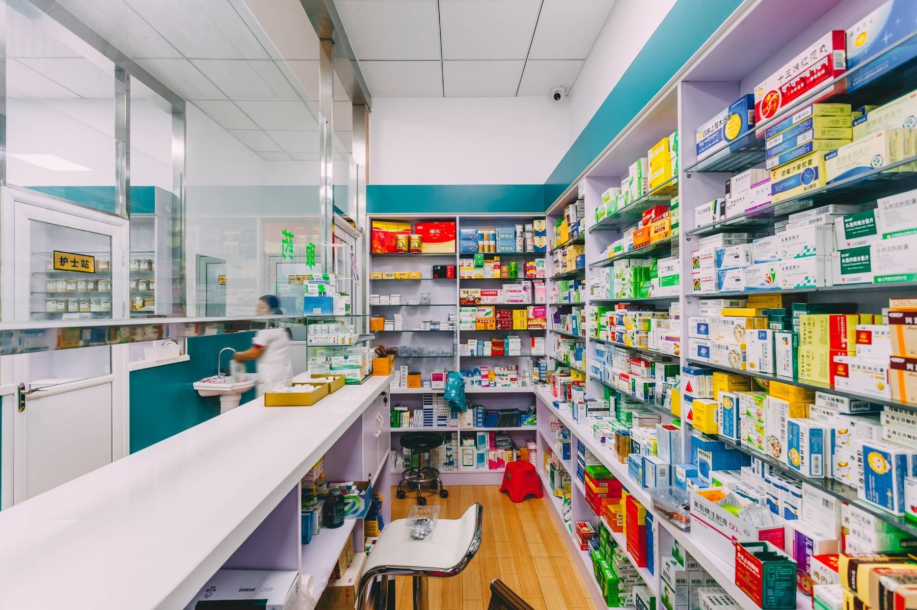 Intérieur d'une officine à Lausanne, comptoir de pharmacie impeccable, rayon parapharmacie ordonné, sol brillant, lumière naturelle, ambiance propre et rassurante.