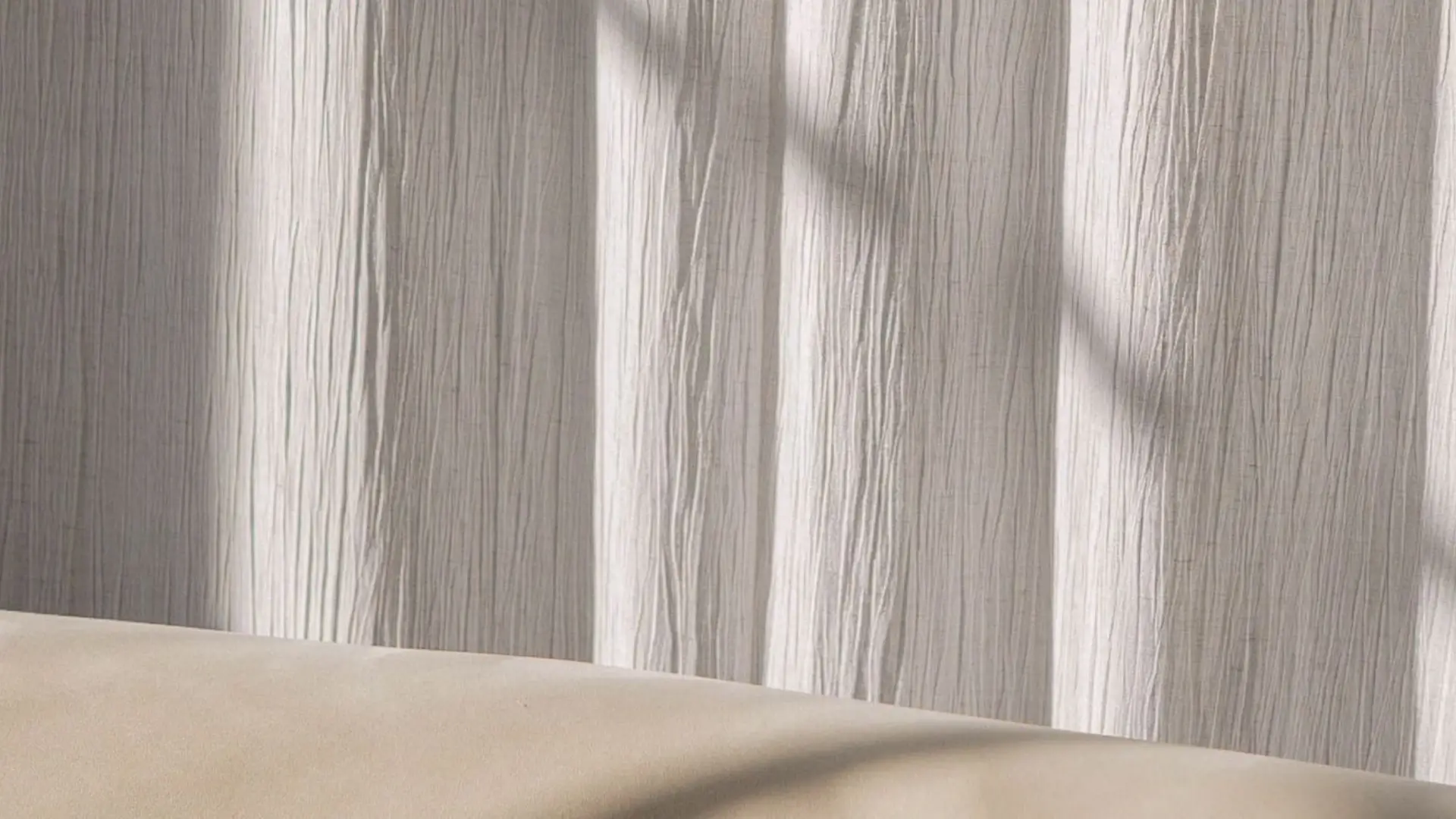 A white couch with a white curtain behind it.