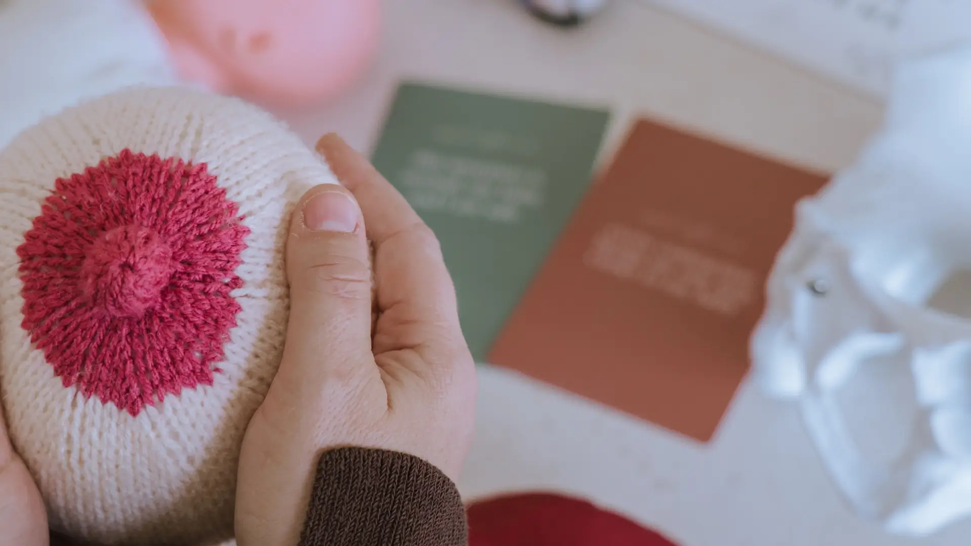 Close-up shot of a midwife's hands holding a knitted breast model used for breastfeeding education and support