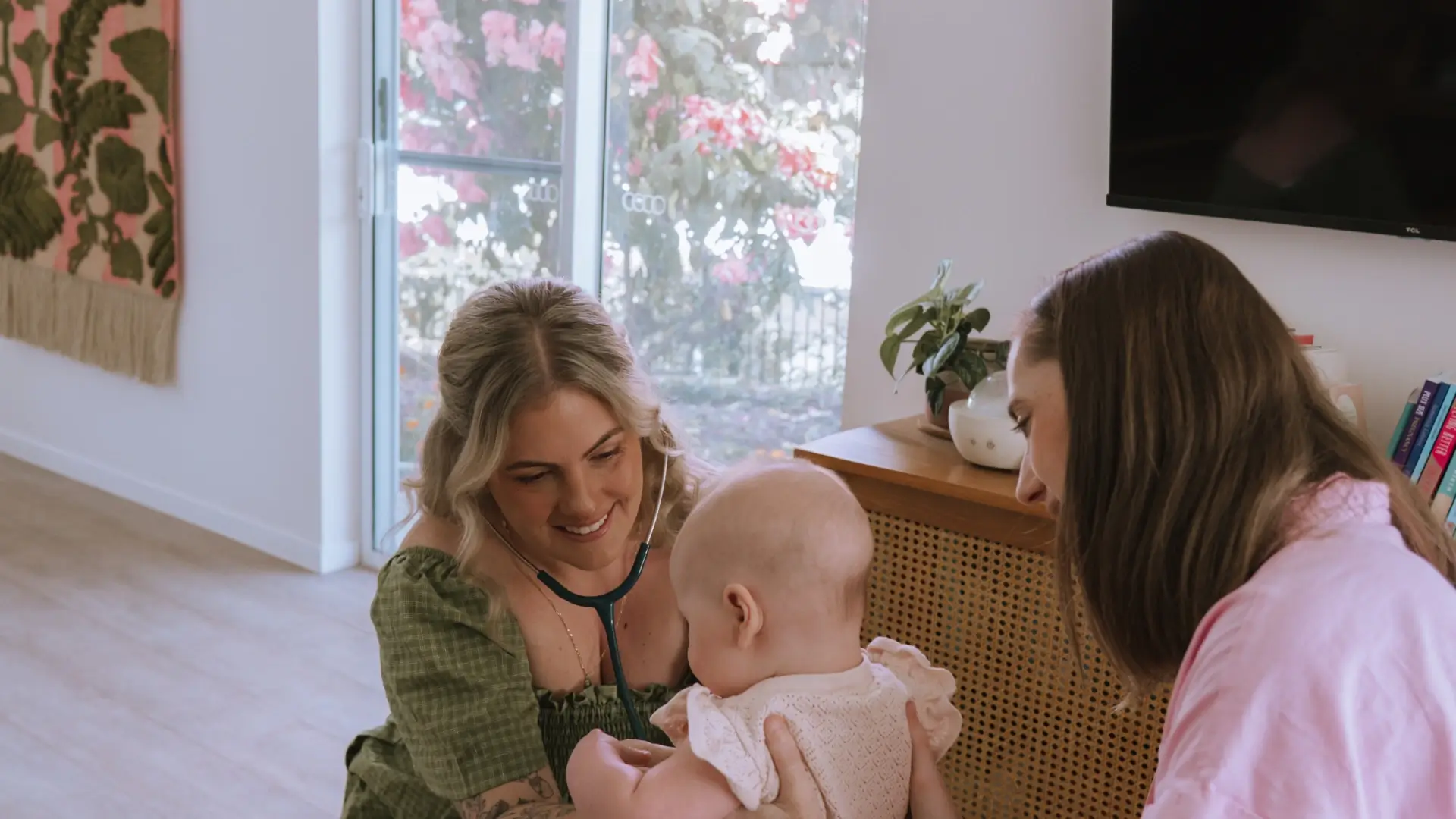 Photo of Caitlin doing physical checkup on a baby held by her mother