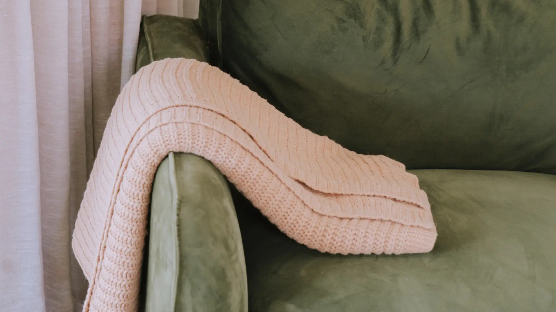 Photo of a pink scarf lying on agreen couch