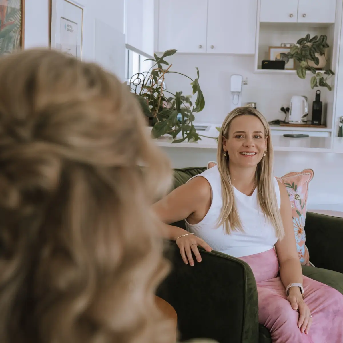 Photo of a woman sitting on a green couch while having birth debriefing with a midwife