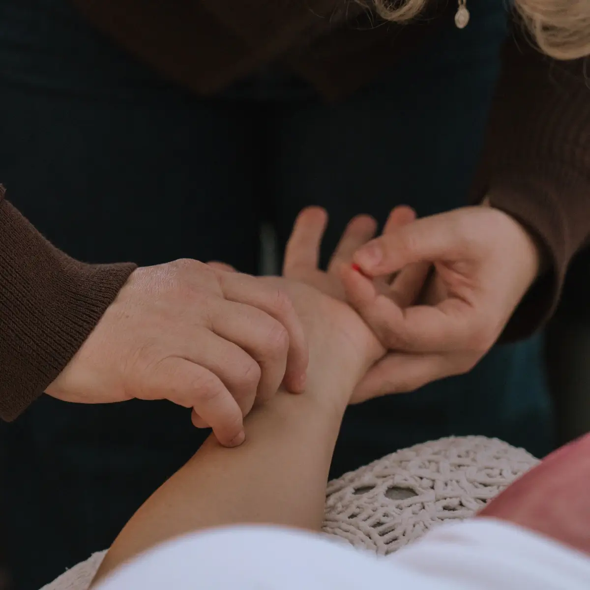 Photo of a midwife's hands performing acuneedling on a client's wrist during a prenatal session