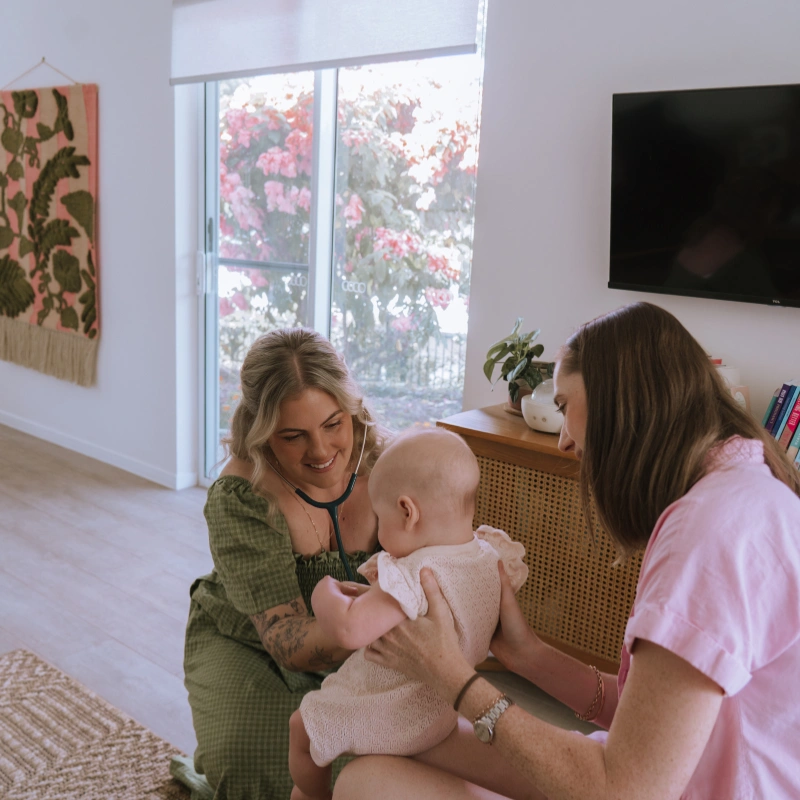 Photo of Caitlin doing physical checkup on a baby held by her mother