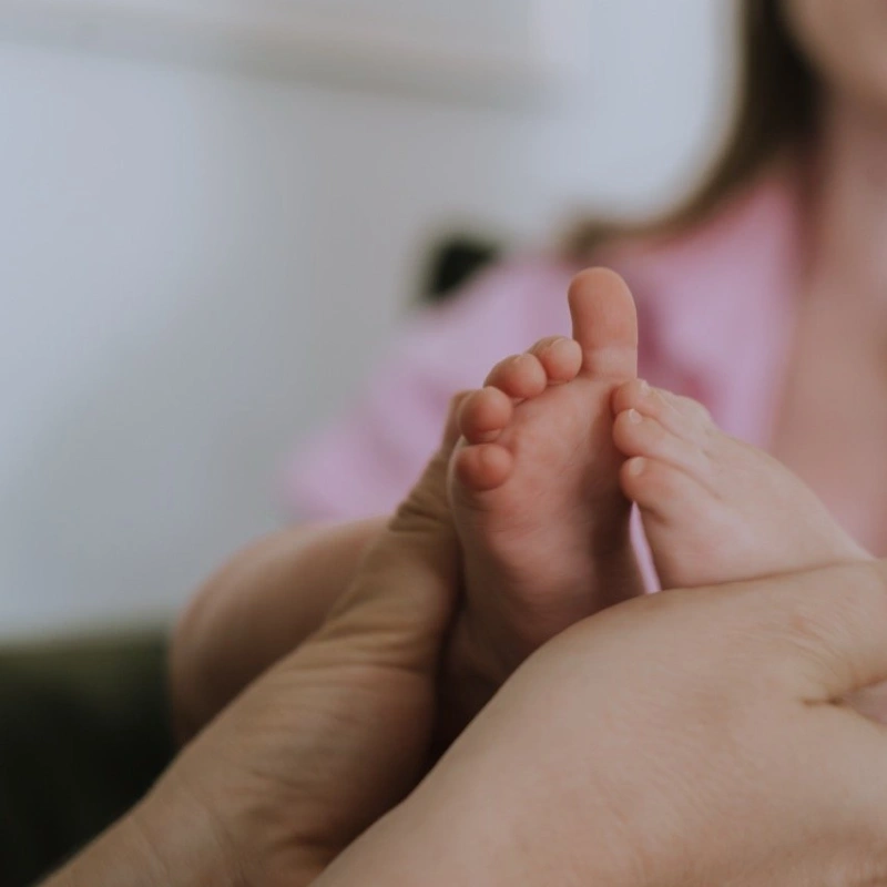 Close-up shot of a midwife's hands gently holding a newborn's tiny feet during checkup